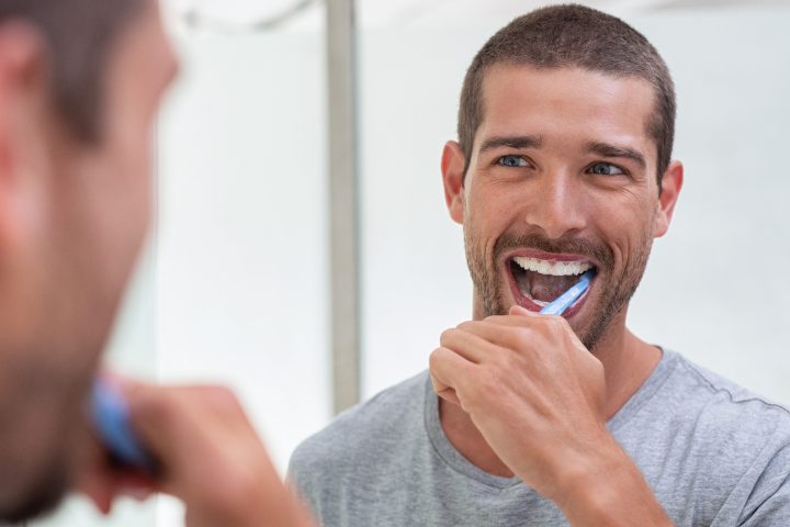 Happy man brushing his teeth