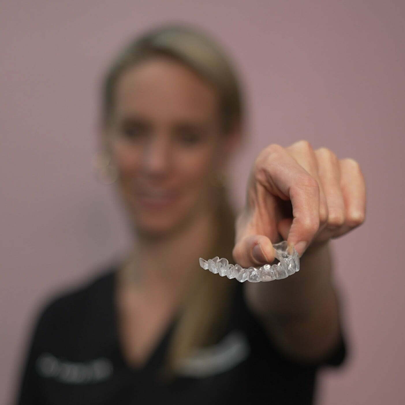 Laura holding Invisalign aligner